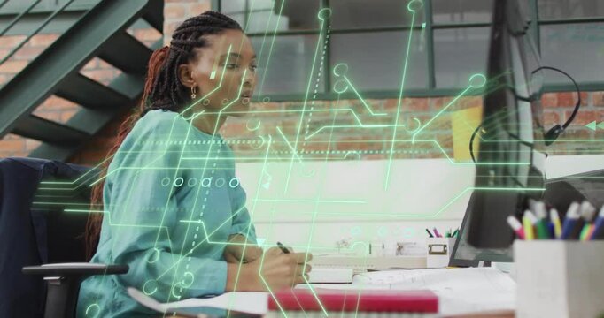 Woman writing at desk in tech office, activating circuit graphics analyzing data and nibbling apple