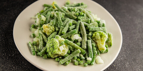 Frozen green vegetables green peas, broccoli, string beans, kohlrabi kale tasty snack fresh food background on the table rustic food top view copy space keto and paleo diet vegan and vegetarian food