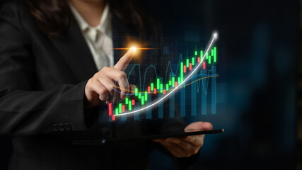 A business professional demonstrates stock market analysis on a tablet, showcasing financial growth through colorful digital charts against a dark backdrop. Impute