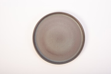 Beautiful ceramic plate placed on a white background, selective focus. Top view.