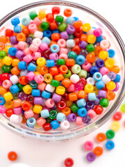 Pony Beads in a rainbow of colors isolated on white in a glass bowl; children's beads for kids crafts