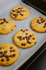 Freshly baked chocolate chip cookies in tray on parchment paper, closeup food photography