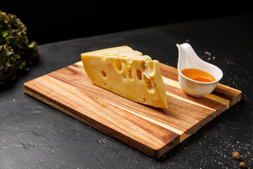 Hard cheese wedge with signature holes, served on board with honey and fresh blueberries
