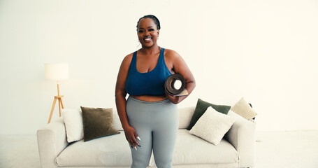 Confident plus size African American woman carries yoga mat