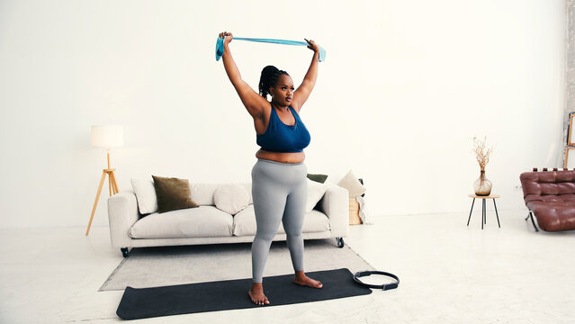 Plus size black woman does strength training with resistance band