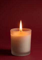 Serene and calming ambiance with a single lit candle in a frosted glass jar providing warm light against a rich burgundy background