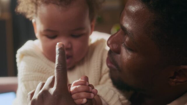 Candid closeup shot of loving African American father booping cute little baby n nose, child looking at camera