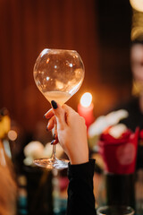 Elegant hand holding wine glass at cozy candlelit dinner with floral decor