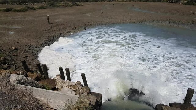 Torrents of water rush through floodgates in the Carboneros marshes, Chiclana de la Frontera, C&aacute;diz, Spain. A dynamic scene of nature, flow, and hydraulic infrastructure.