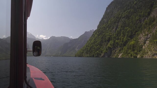 A tranquil boat trip on Lake Koenigssee. The footage from aboard the boat shows the majestic mountains, such as Watzmann, and the clean, green water characteristic of Berchtesgaden National Park