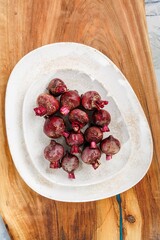 A collection of freshly harvested beets rests upon a white, artisanal plate, set on a wooden cutting board. The vivid reds and purples suggest a bounty of flavor and nutrition