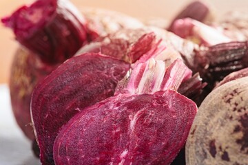 Several beetroots, some whole and some cut into halves, are presented. The deep red of the interior contrasts with the rough, earthy exterior, suggesting freshness and natural goodness