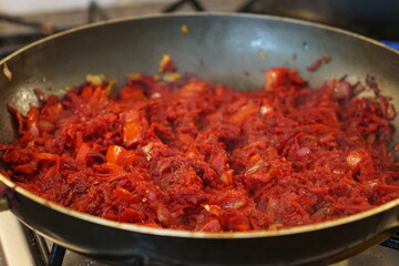 Sauté for borscht made of beets, onions, bell pepper, and carrots in a frying pan.
