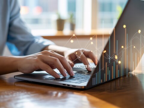 Hands typing on laptop with Analyze Now text and financial graph keyboard