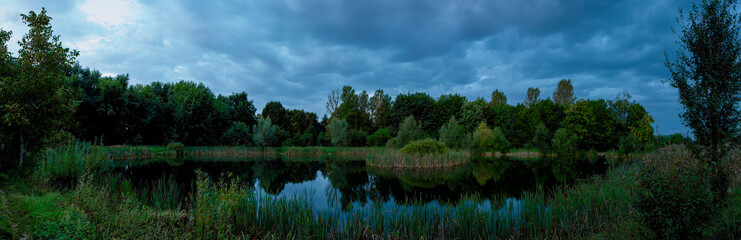 Beautiful panoramic view of the lake in the evening. Mirror reflection in the water. Panorama of a forest lake at dawn.