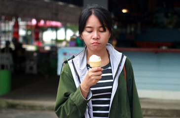 A woman's facial expression showing a feeling of displeasure with his ice cream.