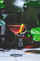 Killer Queen alcoholic cocktail drink with gin, aperitif, bitters, liqueur and lemon twist with bar tools