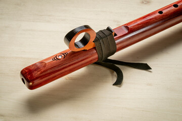 detail of native American style flute with fetish handcrafted from aromatic cedar wood against textured wood © MarekPhotoDesign.com