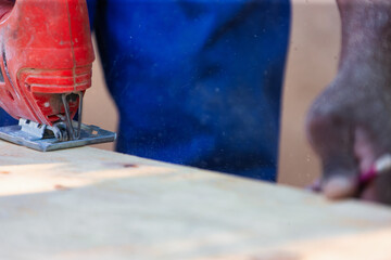 jigsaw cutting plank wood, african american man carpenter in the workshop, holding power tools