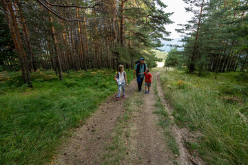 A father and two children are walking uphill in the forest. Happy family lifestyle, outdoor...