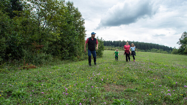 Hiking in the mountains. Family time, happiness, joy, fun moments. Diverse family bonding in nature while exploring green forest path. 