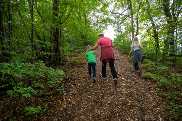 Walking in the woods. A woman and two kids in the forest. Summer family outdoor activities.