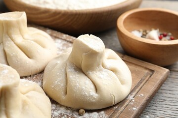 Uncooked khinkalis (dumplings) on wooden table, closeup