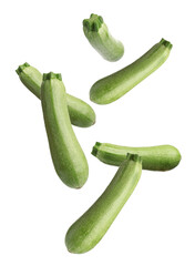 Fresh ripe zucchinis falling on white background