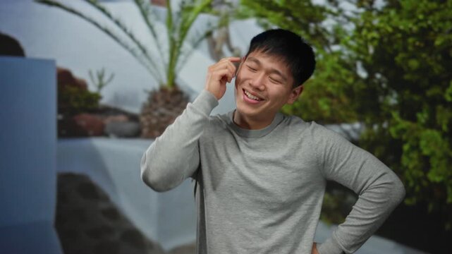 Young man outdoors in a park smiles confidently while gesturing as if having an idea against a natural green background, capturing a moment of inspiration and happiness.