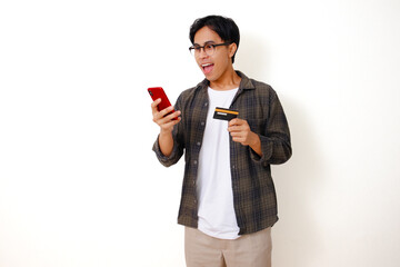 Surprised Asian man holding a product card while using his phone, showing a happy and excited expression