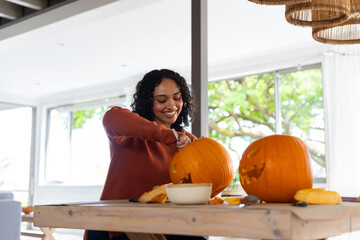Halloween time, Carving pumpkins at home, woman preparing for Thanksgiving celebration with smile