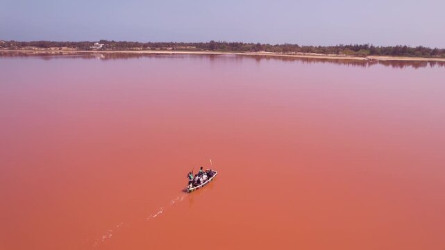 SENEGAL - 7.14.2025 - Stunning aerial view following a man as he rows a boat down Dakar, Senegal's Pink Lake.