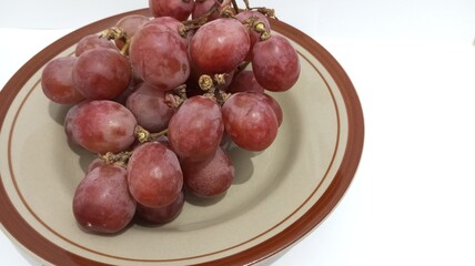 red grapes on a plate with a white background
