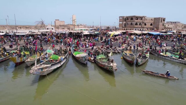 SENEGAL - 7.16.2025 - Great aerial footage of fishing boats pulling up to a fish market on Senegal's Island of Saint-Louis.