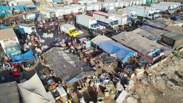 SENEGAL - 7.16.2025 - Very good aerial footage circling counterclockwise towards refrigerated trucks at a fish market on Senegal's Island of Saint-Louis.