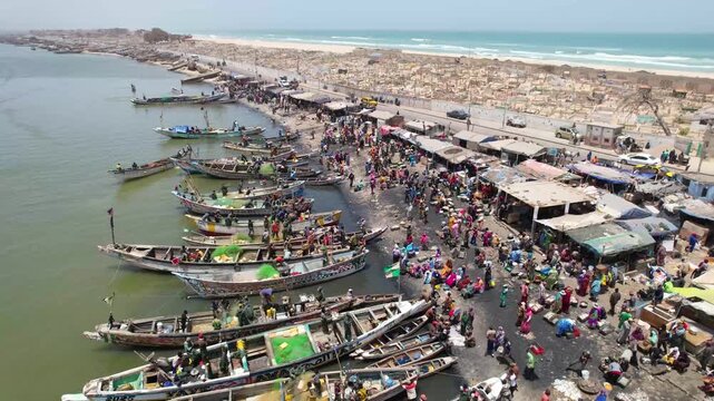 SENEGAL - 7.16.2025 - Very good aerial footage of a rowboat approaching a fish market on Senegal's Island of Saint-Louis.