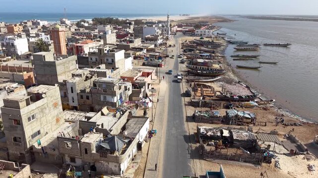 SENEGAL - 7.16.2025 - Excellent aerial moving up a harbor on Senegal's Island of Saint-Louis, headed towards a mosque.
