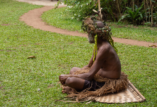 A elder villager wearing the traditional skirt and headwear made of natural fibers, sitting on a paln tree mat, Keamu village, Aneityum Island, Tafea, Vanuatu, South Pacific Ocean