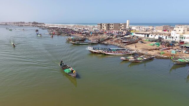 SENEGAL - 7.16.2025 - Wonderful aerial footage of powerboats sailing past a busy harbor on Senegal's Island of Saint-Louis.