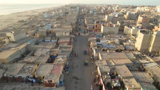 SENEGAL - 7.16.2025 - Excellent aerial footage moving up a busy road on Senegal's Island of Saint-Louis, driven on by horse-drawn carts.