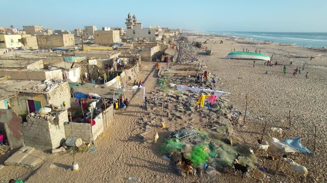 SENEGAL - 7.16.2025 - Excellent aerial footage moving up a beachside neighborhood where people are putting up their laundry on Senegal's Island of Saint-Louis.