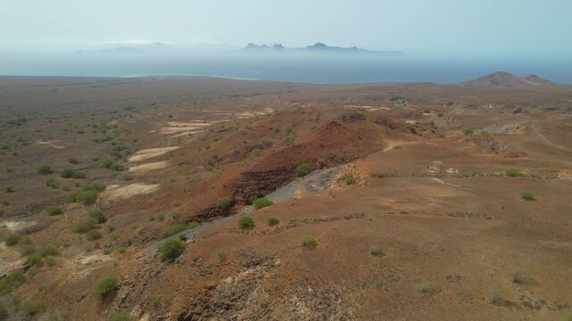 CAPE VERDE - 8.20.2025 - Stunning aerial footage passing over dry landscapes of Santo Antao Island with a view of Sao Vicente in the misty distance.