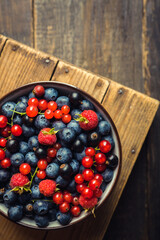 Freshly harvested berries in bowl on the rustic background. Summer berries. Shot from above.