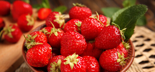 Bowl with sweet ripe strawberries and mint leaf on wooden background, closeup