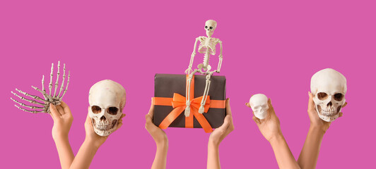 Female hands with Halloween gift, skeleton, hand and skulls on purple background