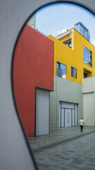 Person Walking Through Colorful Urban Courtyard Viewed Through Circular Frame