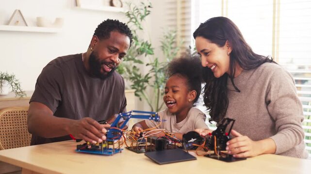 Happy parents and daughter building robotics project together at home, concept of stem education, creativity, teamwork and family bonding in bright room