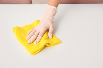Young woman cleaning white table