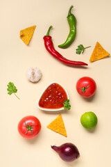 Bowl with tasty salsa sauce, nachos and ingredients on yellow background