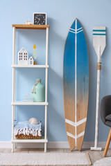Interior of stylish living room with grey armchair and surfboard